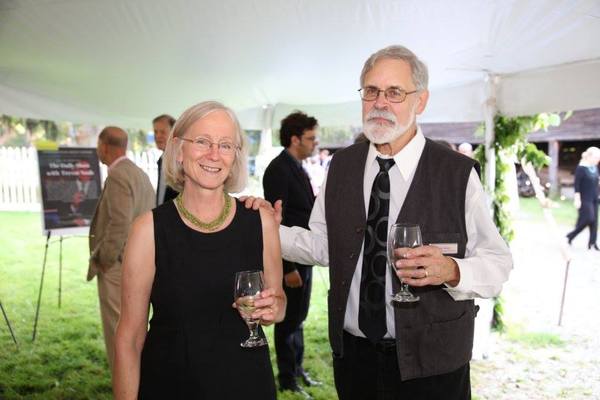 A man and woman standing in front of a tent with wine glasses.