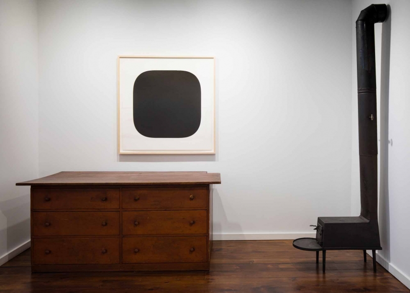 A black painting and a wooden desk in an art gallery.