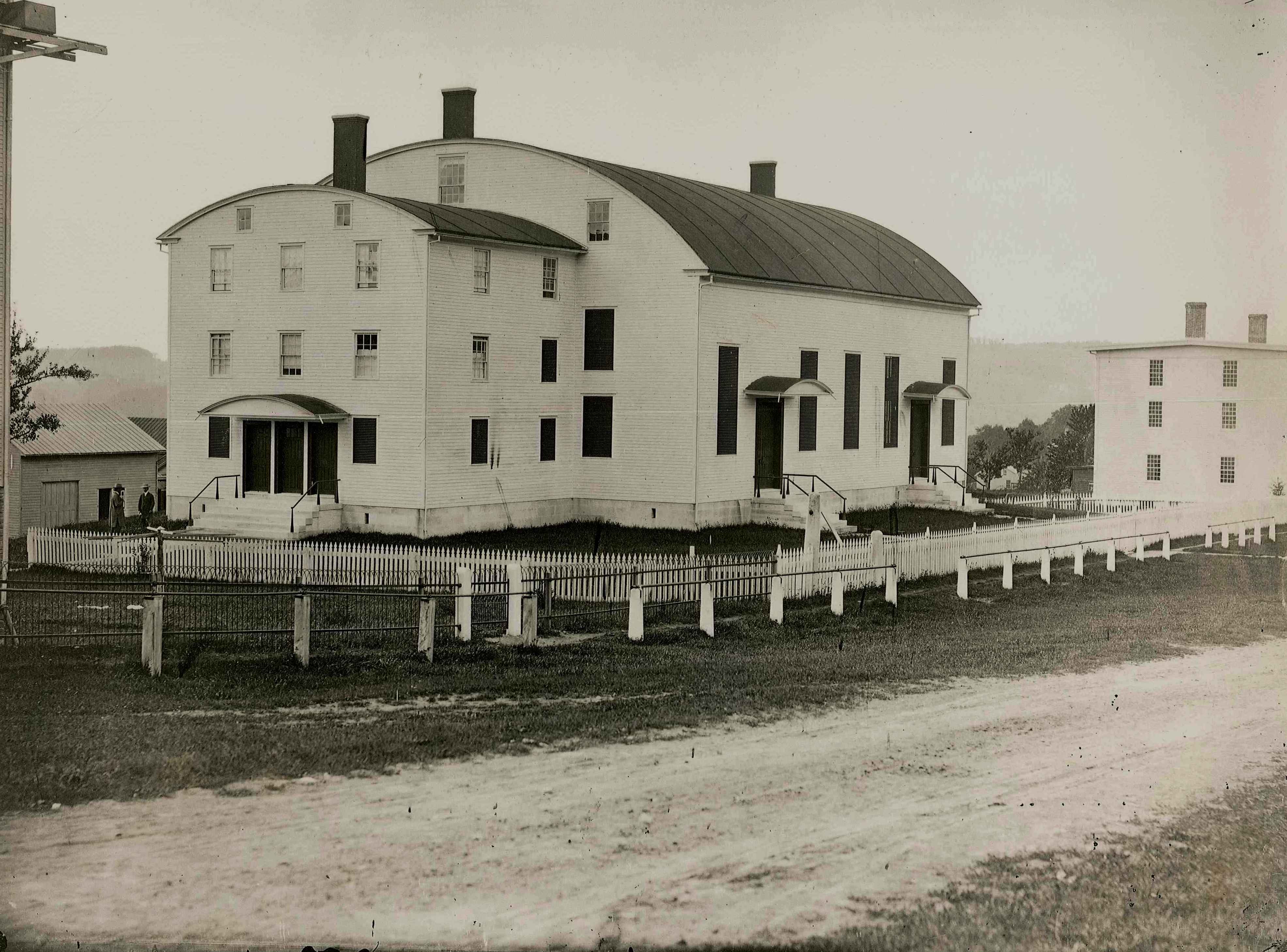 An old photo of a white house on a farm.