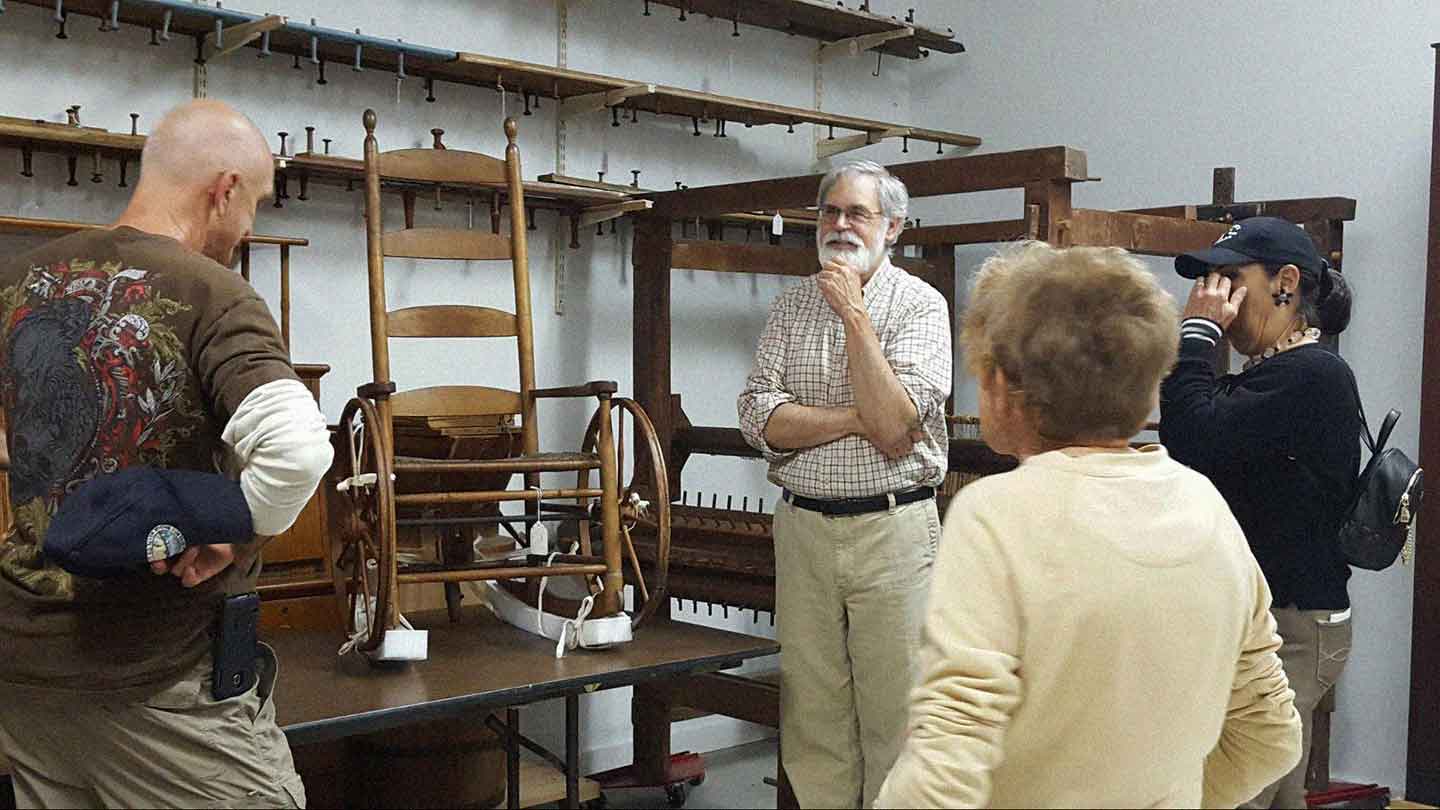 A group of people standing around a room full of furniture.