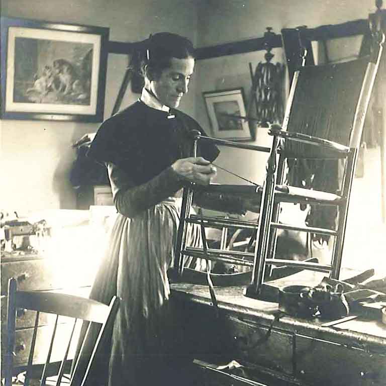 An old photo of a woman making a chair.