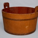 A wooden bucket with handles on a gray background.