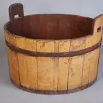 An old wooden bucket with handles on it.