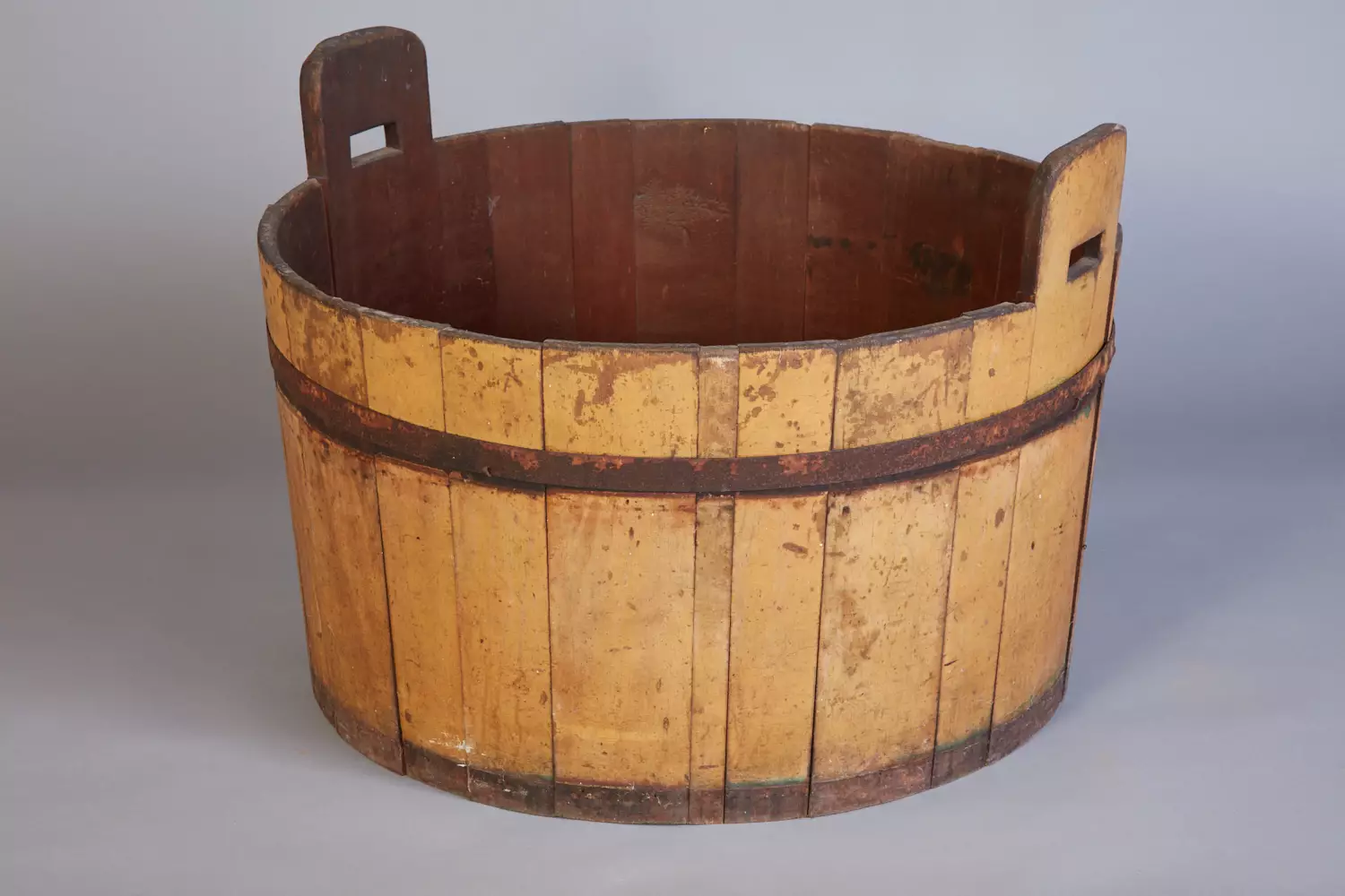 An old wooden bucket with handles on it.