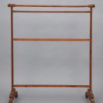 A wooden clothes rack on a gray background.