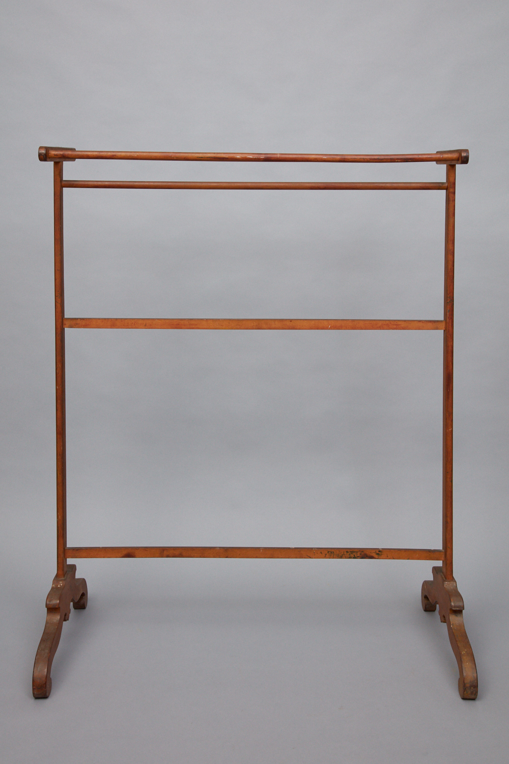 A wooden clothes rack on a gray background.