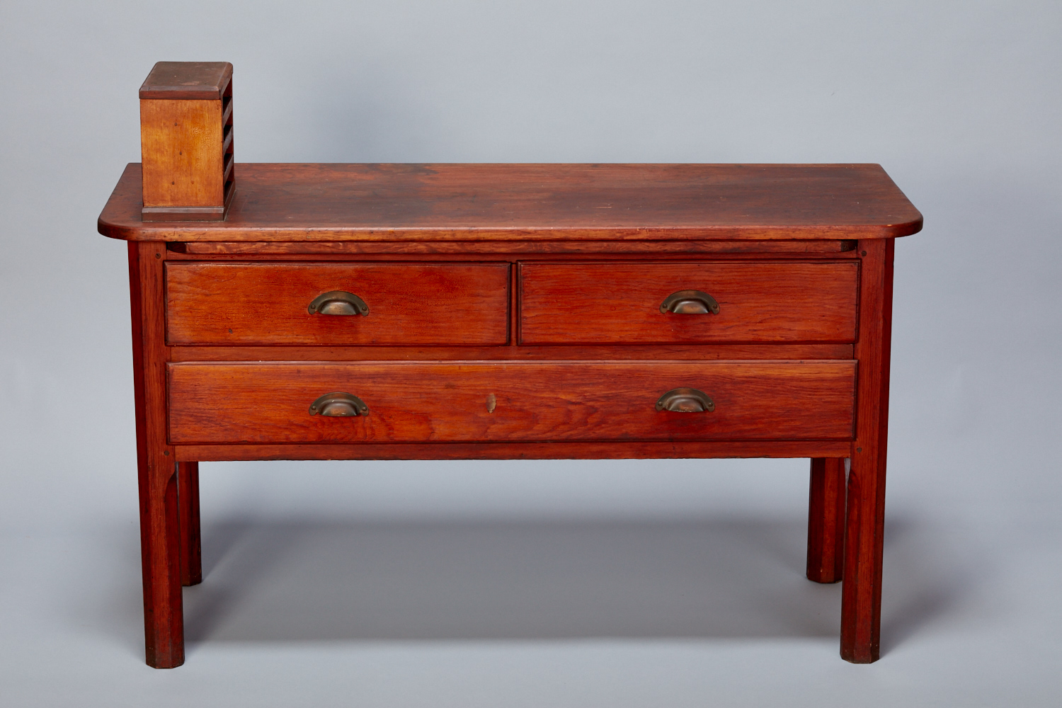 A small wooden chest of drawers with a box on top.