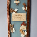 A wooden frame with dried leaves and a note.