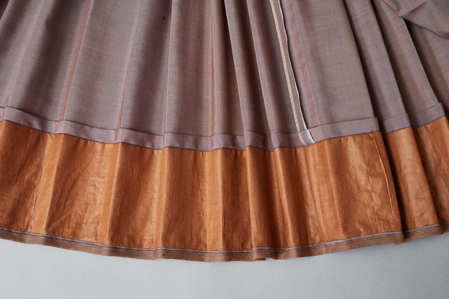 A grey and orange skirt hanging on a wall.