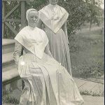 Two women dressed in white sitting on steps.