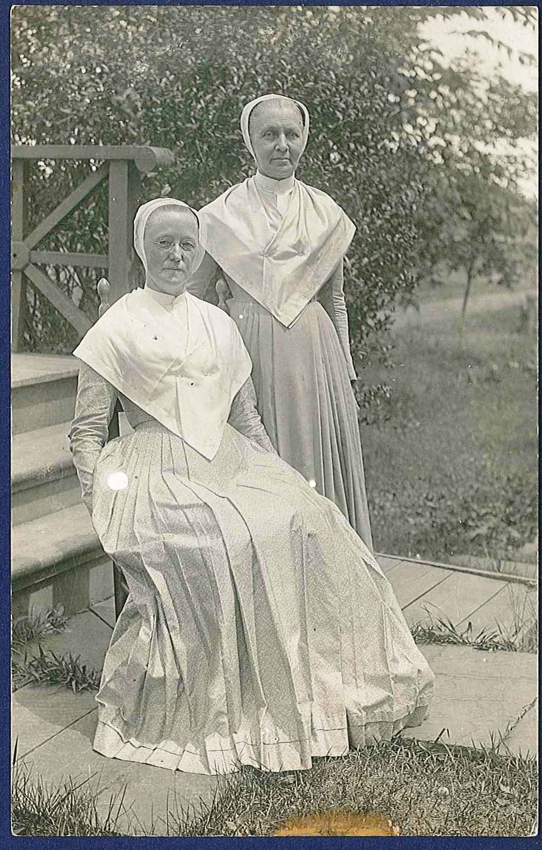 Two women dressed in white sitting on steps.