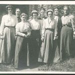 A group of women standing in front of a house.