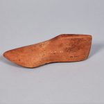 A small wooden shoe on a grey surface.