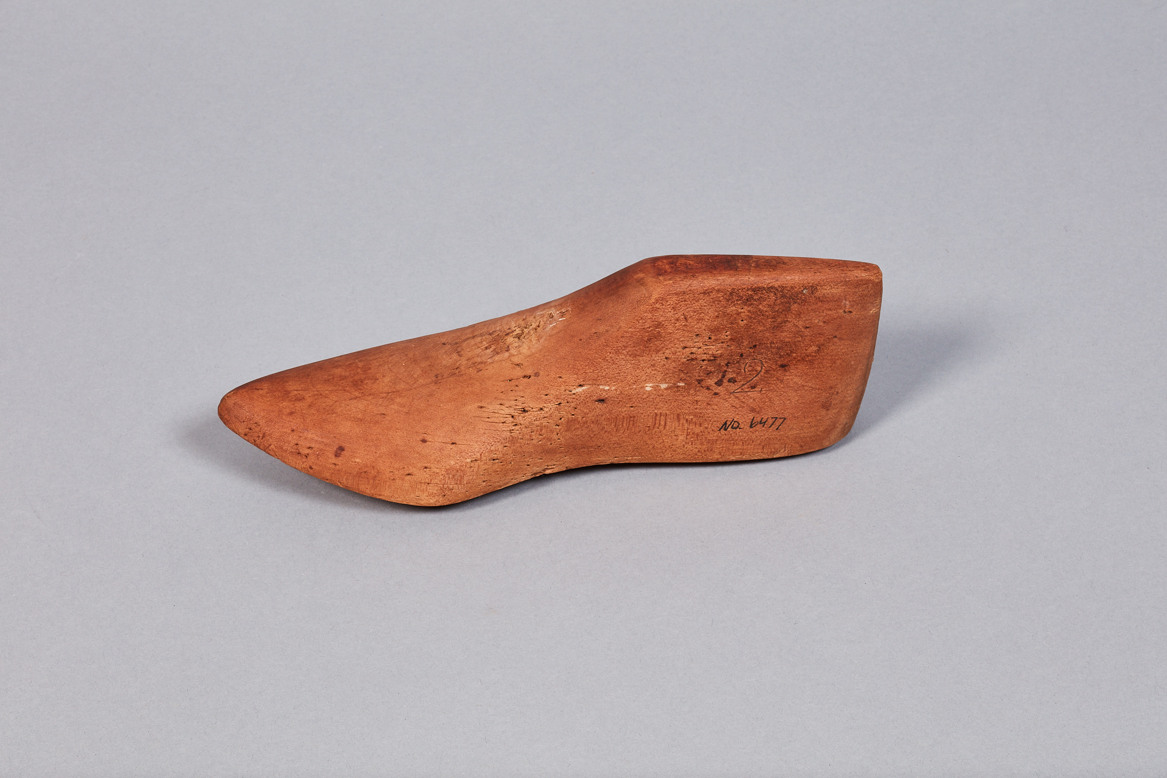 A small wooden shoe on a grey surface.