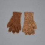 A pair of brown wool gloves on a gray surface.