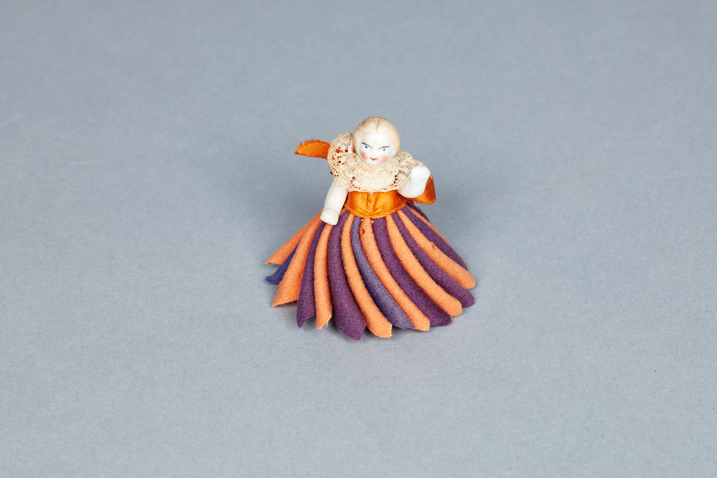 A figurine of a woman in an orange and purple dress.