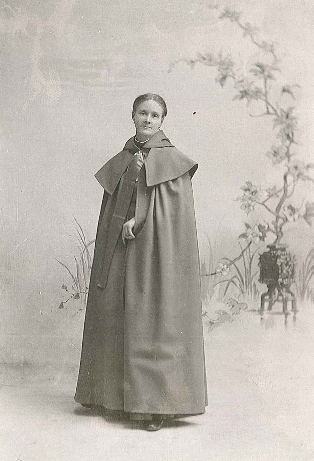 An old photo of a woman in a cloak.