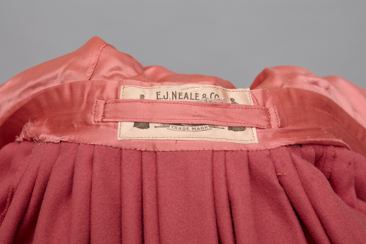 A pink silk dress with a label on it.