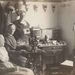 Three women in a room with a sewing machine.