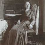 An old photo of a woman sitting in a chair.