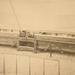 An old photo of a wooden bed in a room.