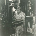 An old photo of a woman working in a factory.