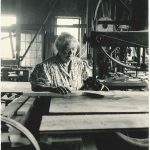 An old black and white photo of a woman working in a factory.