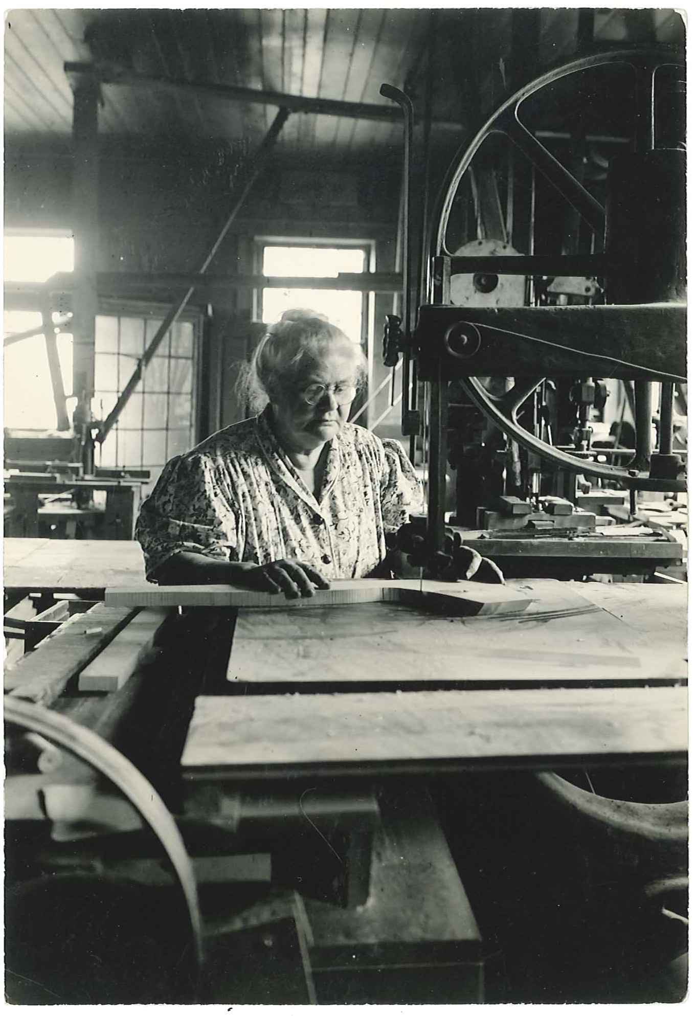 An old black and white photo of a woman working in a factory.