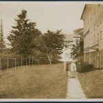 A woman walking down a path next to a house.