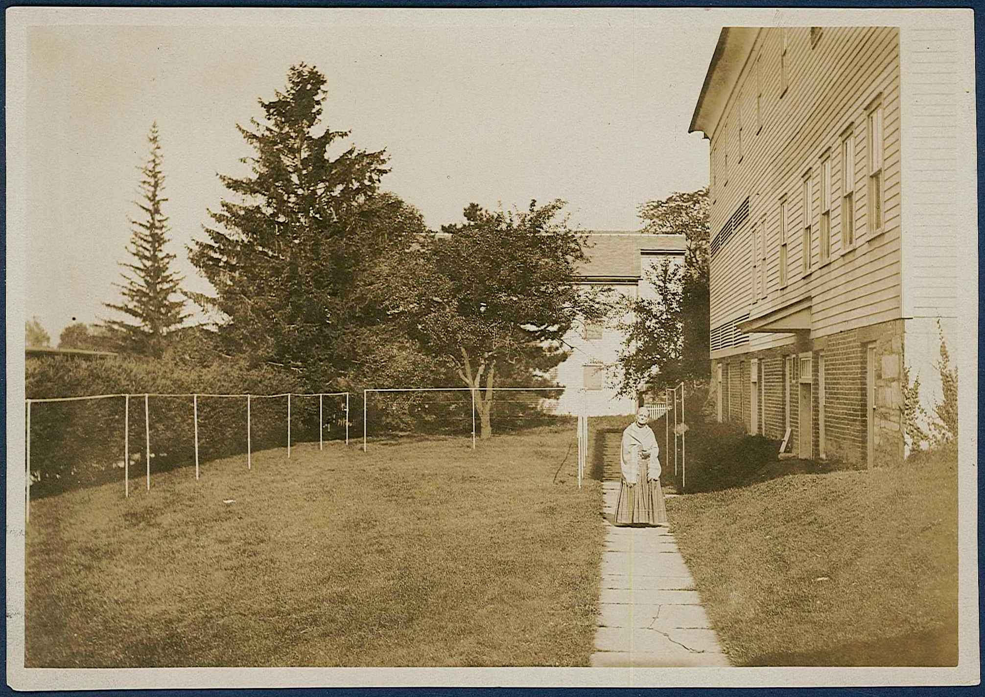 A woman walking down a path next to a house.