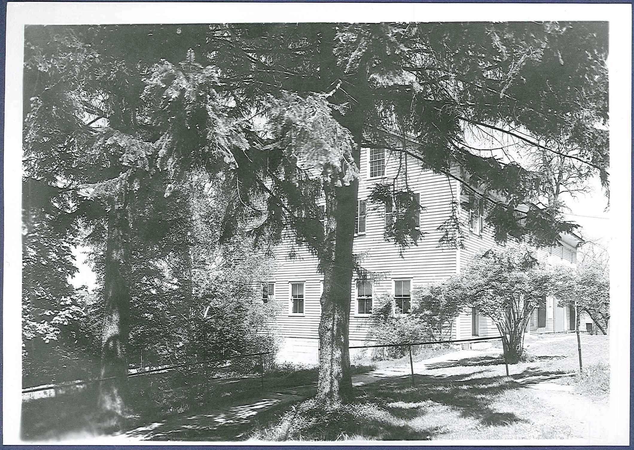 A black and white photo of a house with trees.