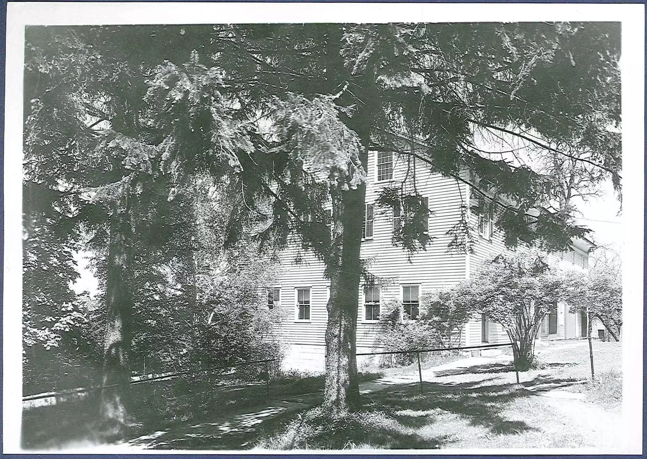 A black and white photo of a house with trees.