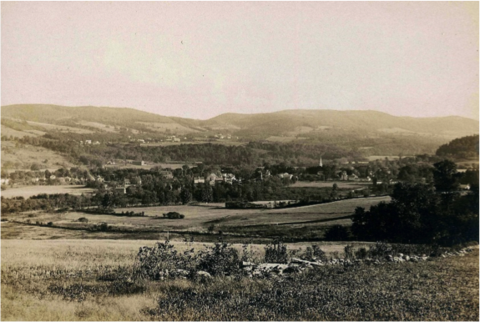 An old black and white photo of a field and hills.