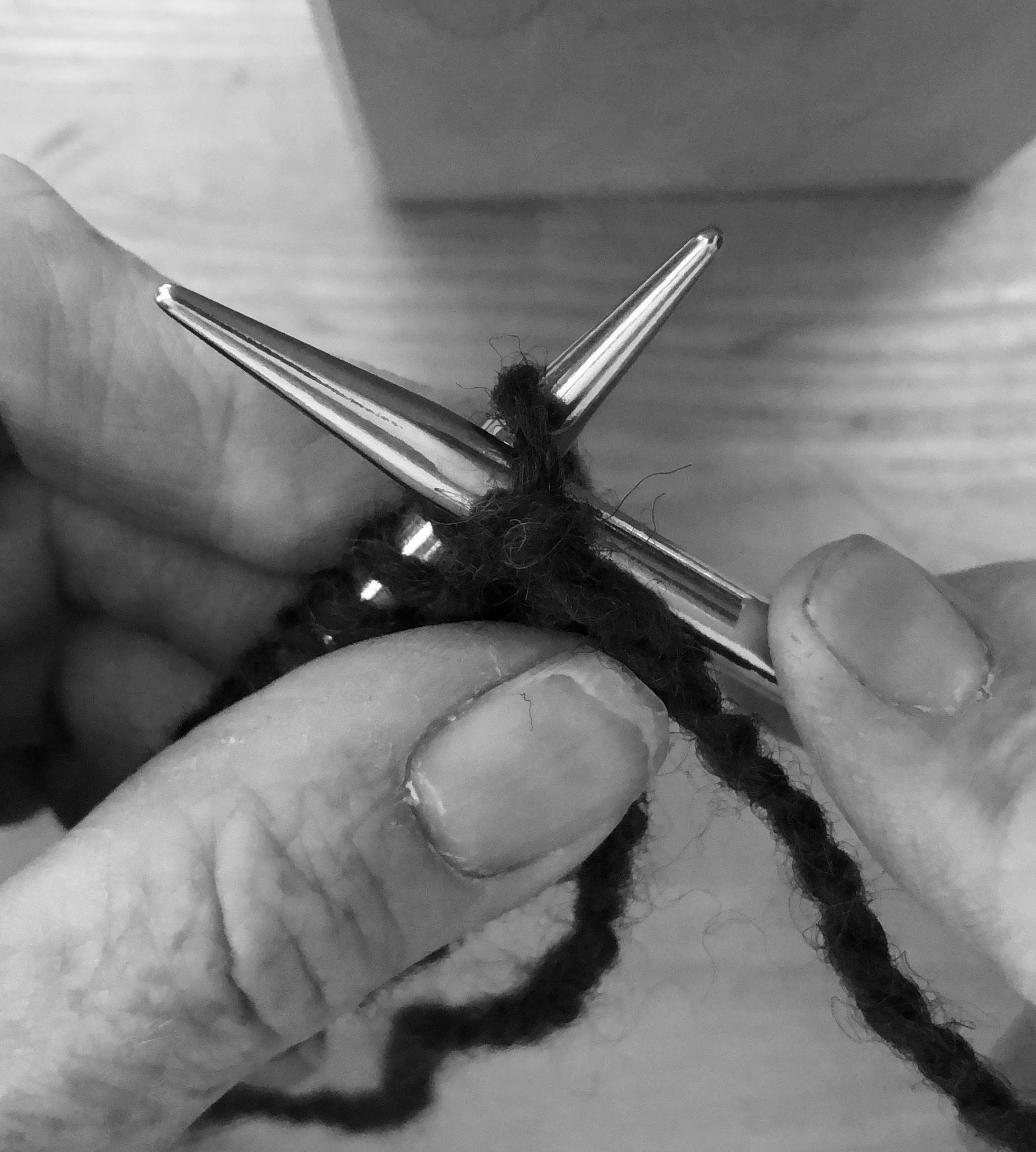 A black and white photo of a person holding a knitting needle.