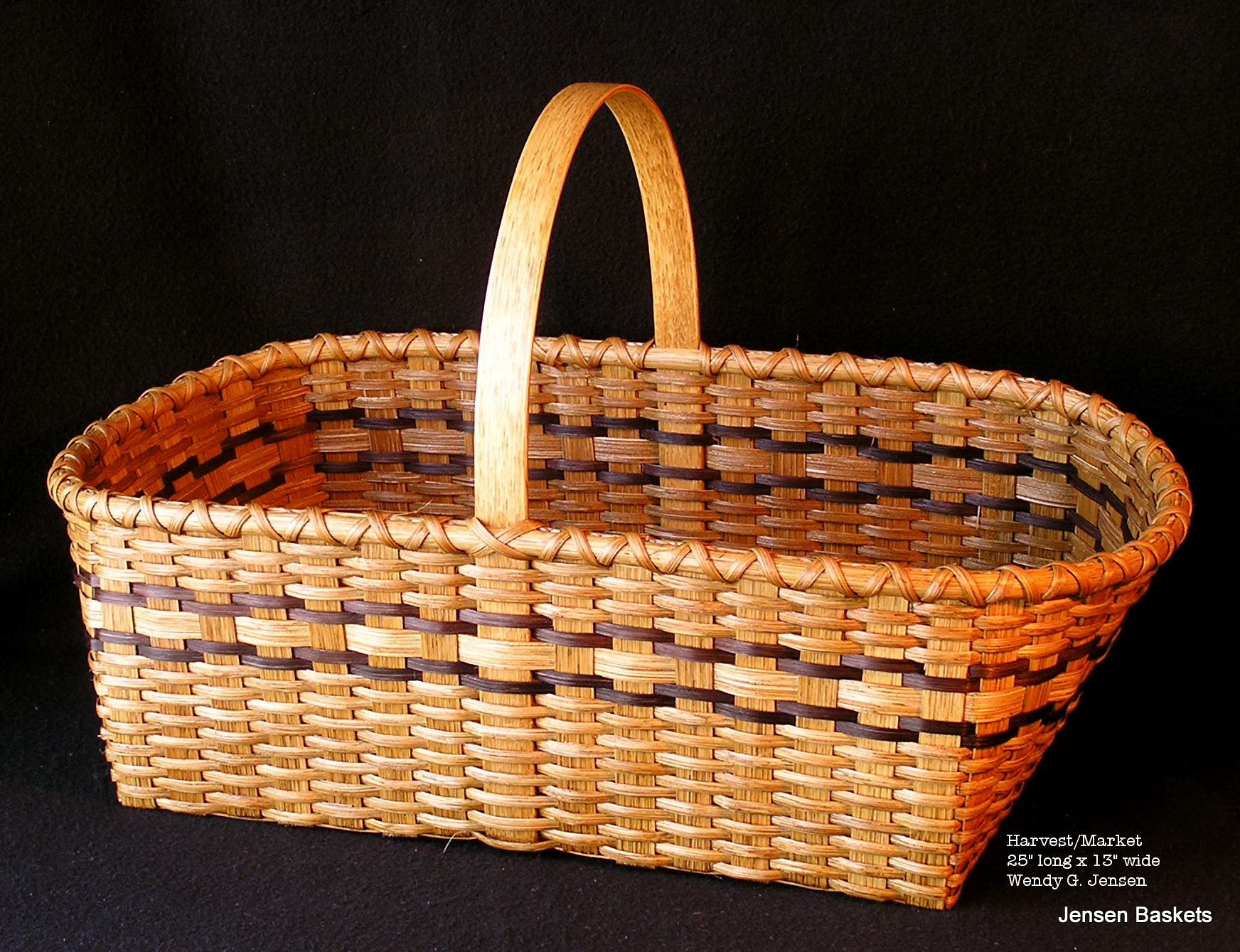 A wicker basket with handles on a black background.