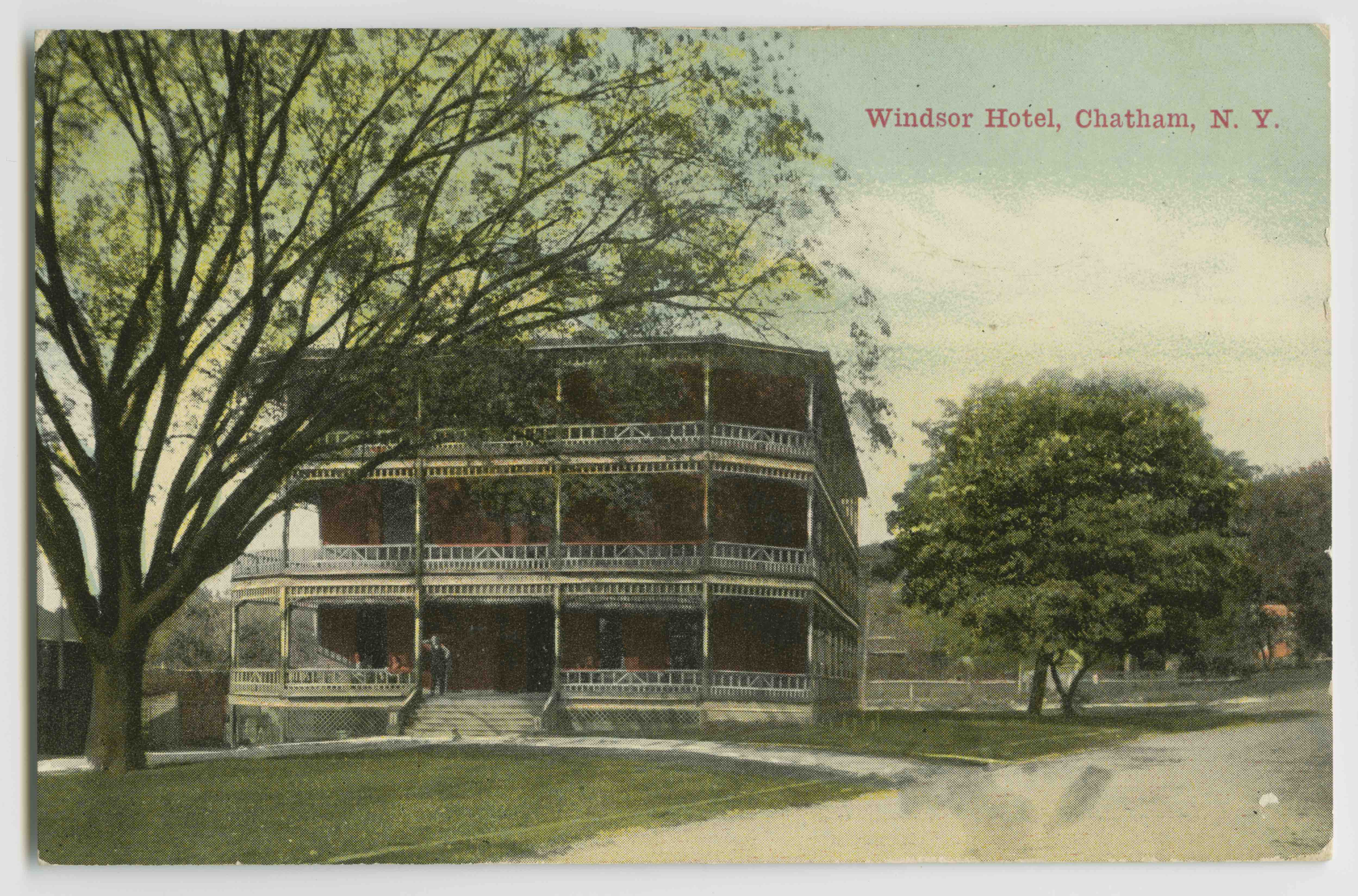 A postcard of a house with a tree in the background.