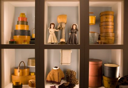 A display of dolls in a glass case.