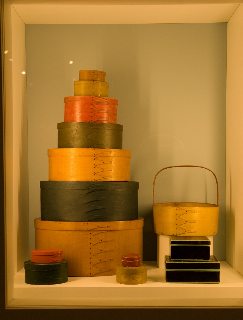 A stack of wooden boxes on display in a glass case.