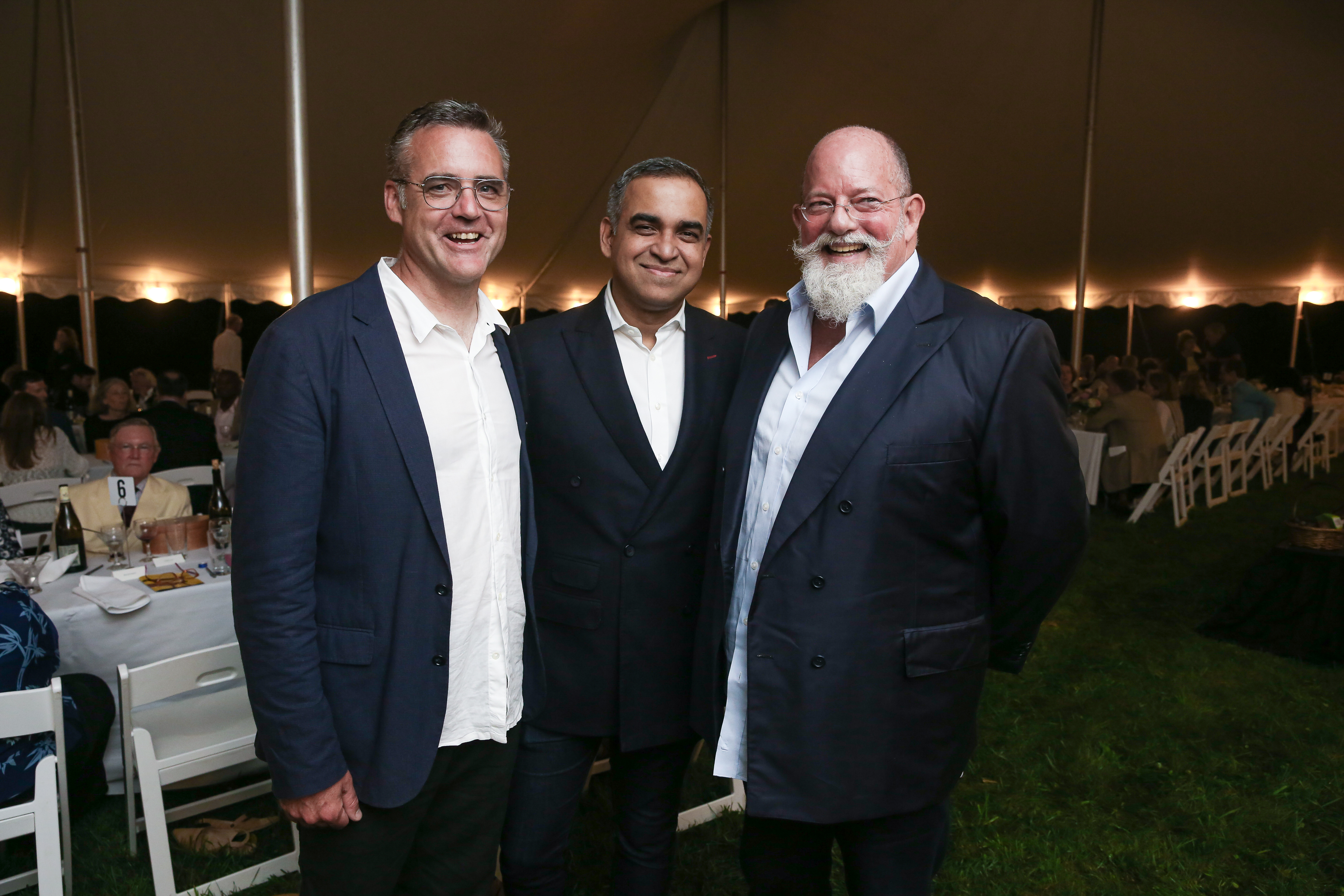 Three men standing next to each other in a tent.
