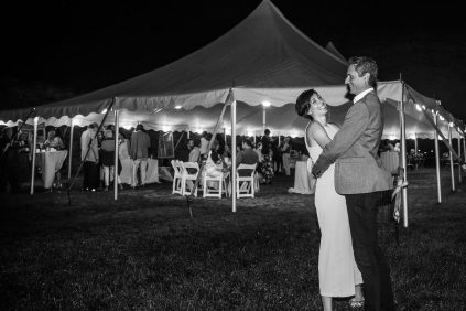 A bride and groom dancing under a tent.
