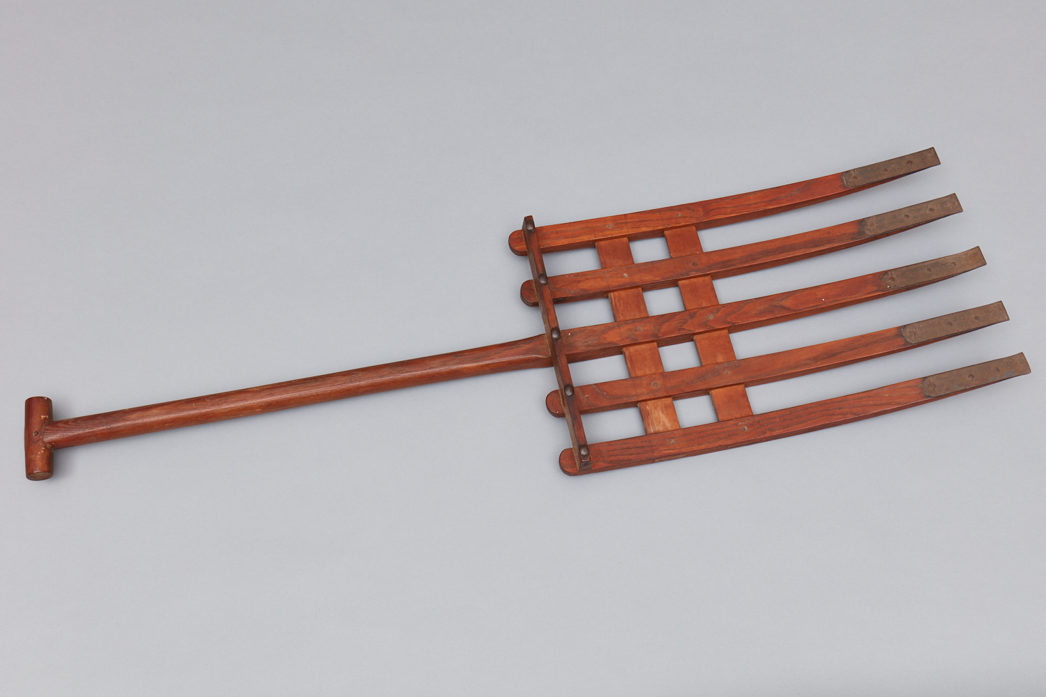 A wooden pitchfork with four blades.