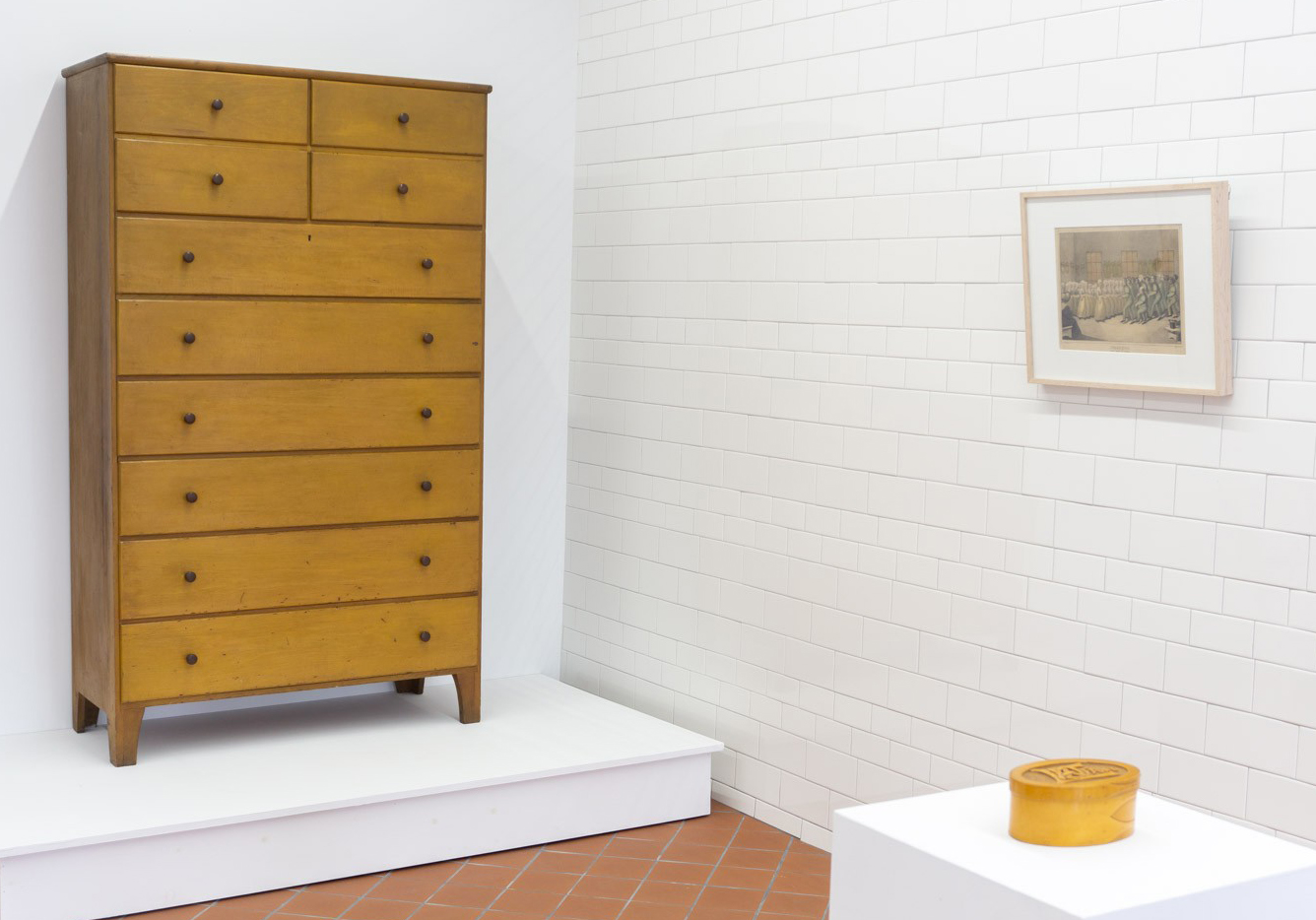 A yellow dresser is on display in a white room.