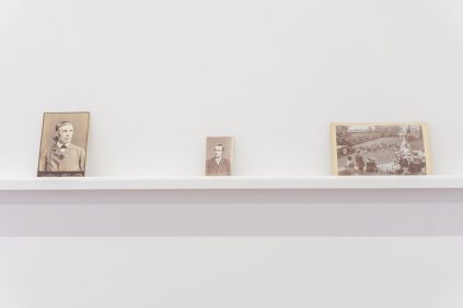 Three photographs on a shelf in a white room.