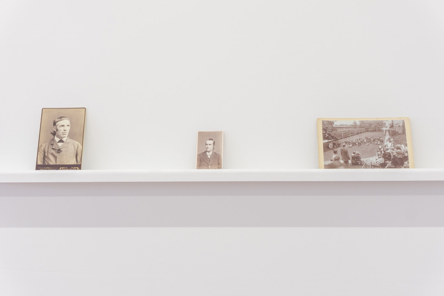 Three photographs on a shelf in a white room.