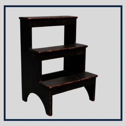 A black step stool with a shelf on top.