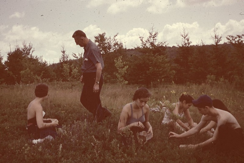 A group of people sitting in a field with a man.