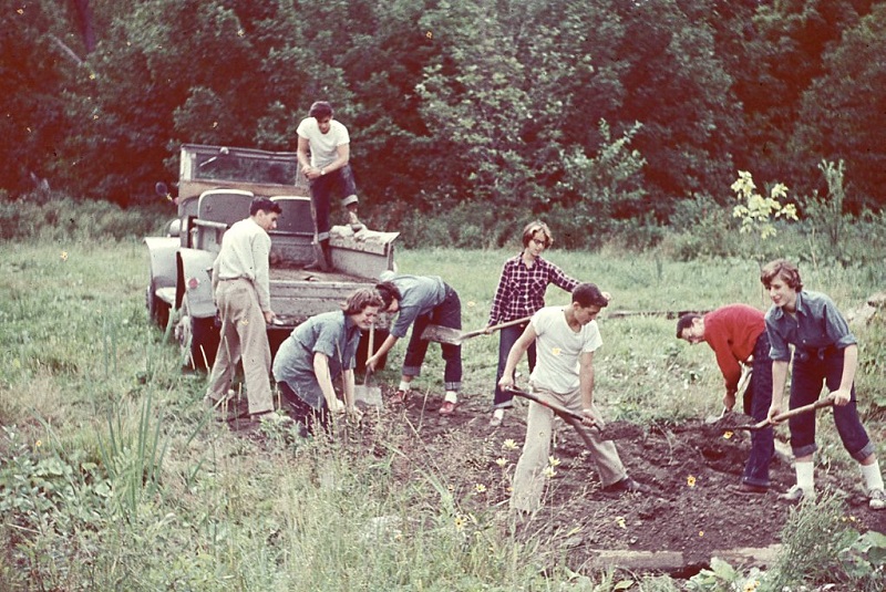 A group of people working in a field with shovels.