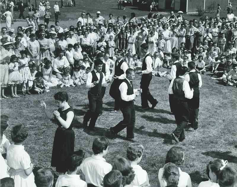 A group of people dancing in front of a large crowd.