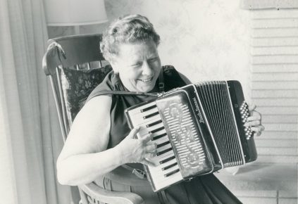 An old black and white photo of a woman playing an accordion.