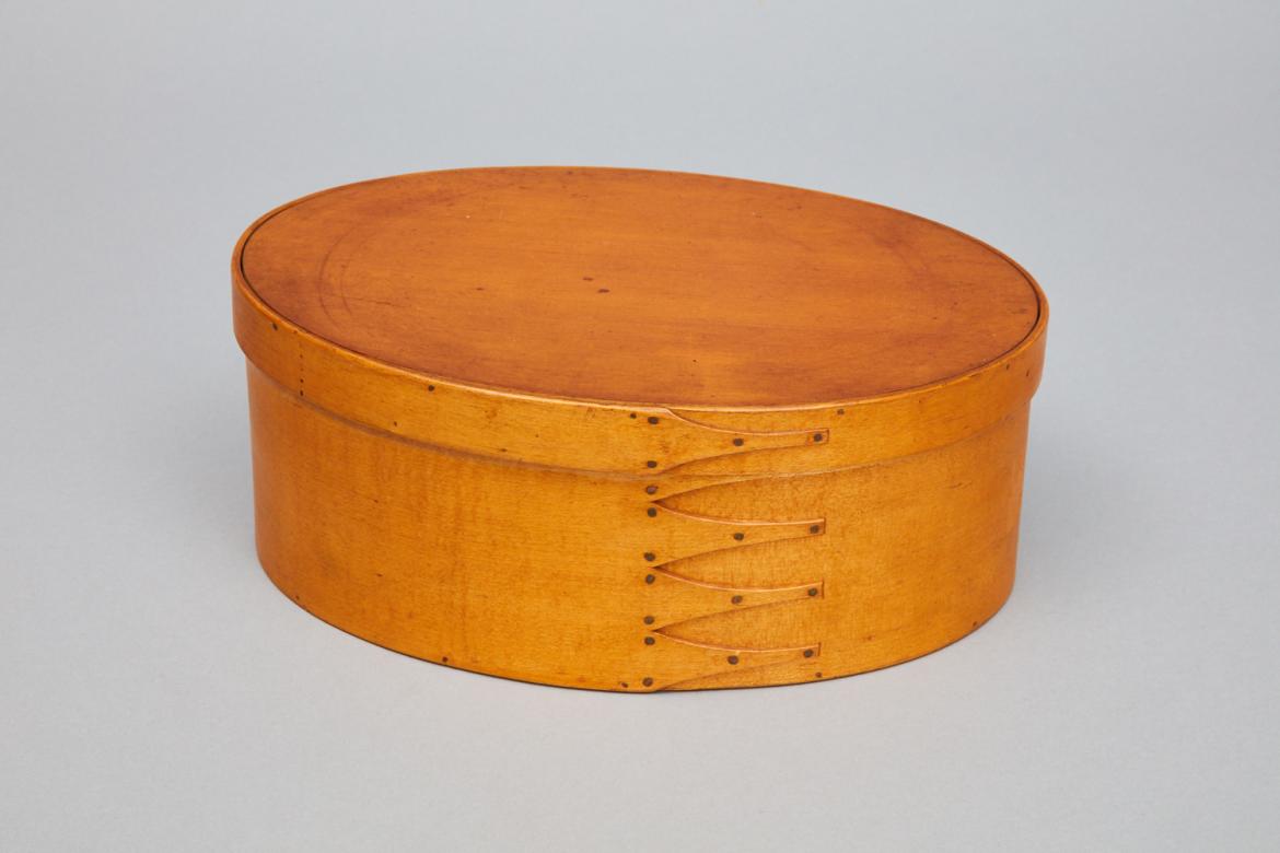An oval wooden box on a white surface.